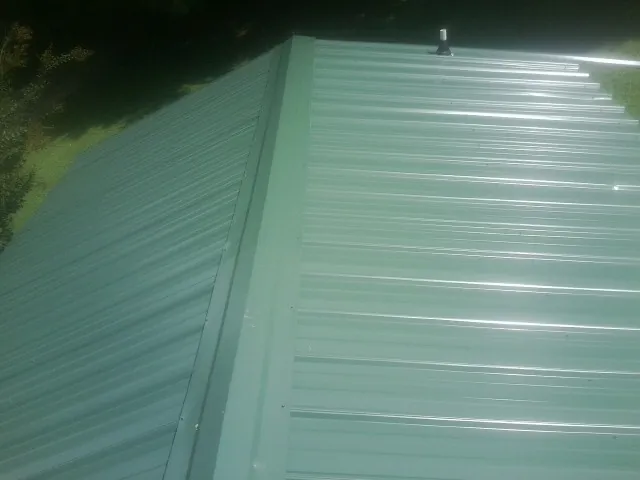 New green metal panels meeting at the ridge of a roof — Flat Roof Repair work by our crew in Ridgeland